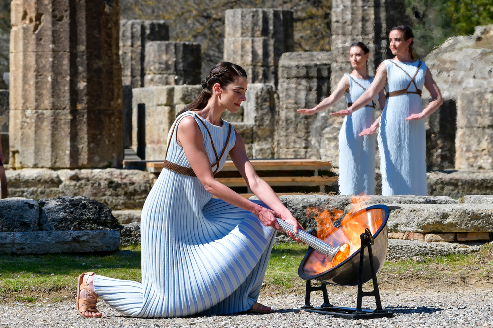 Woman lighting olympic torch in Greece